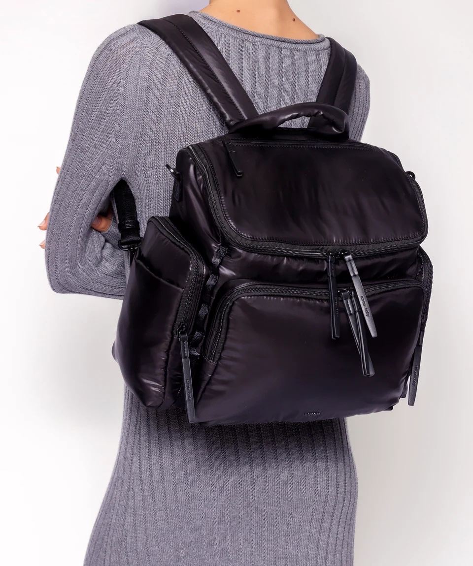 A woman seen from the back wearing a black puffy nylon backpack.