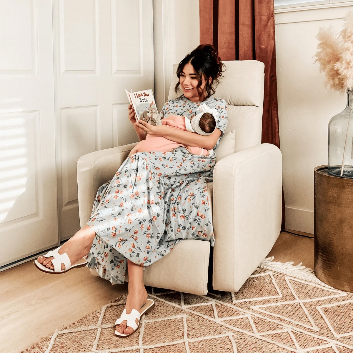 A woman sitting in a fabric rocking chair holding a baby.