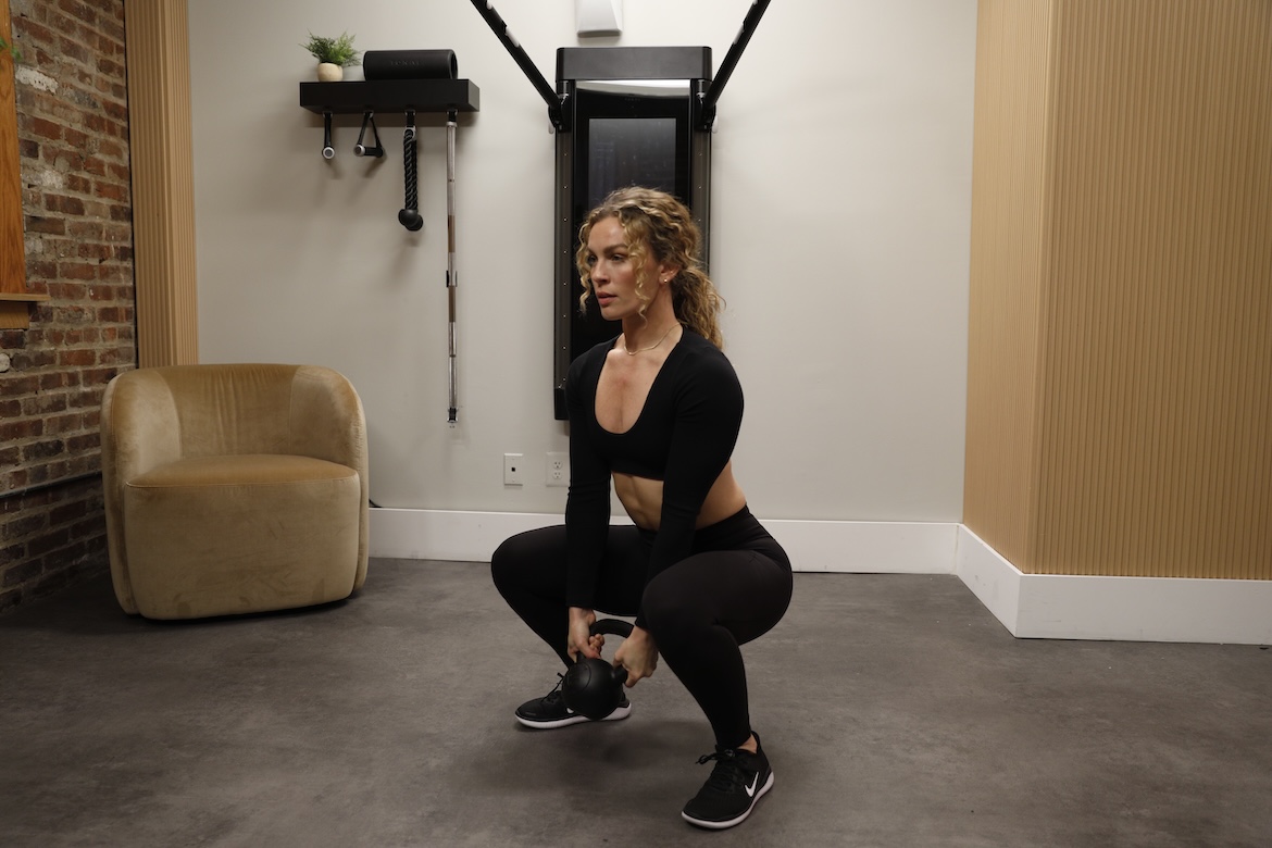 Personal trainer demonstrating goblet squat with biceps curl