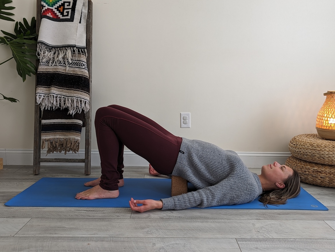 Yoga teacher demonstrating supported bridge pose