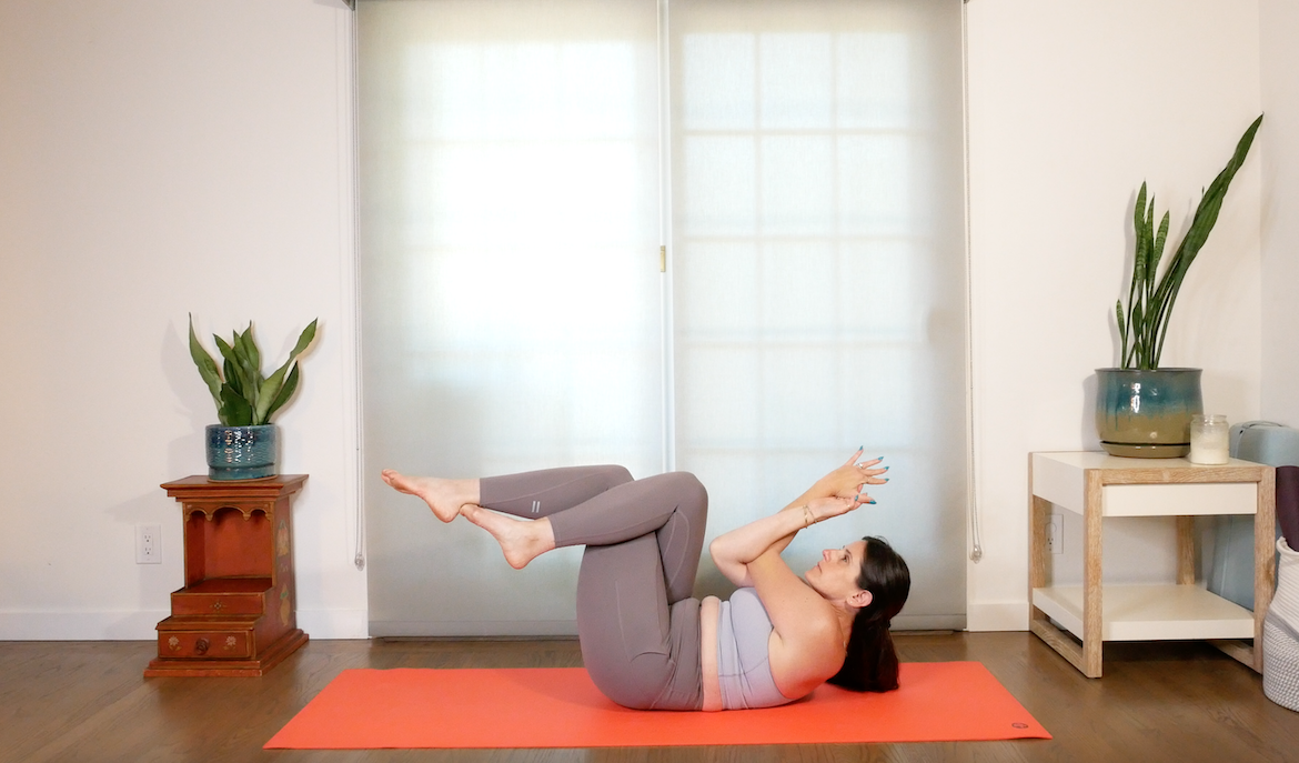 professora de ioga demonstra como realizar o crunch da águia na ioga, com as costas em um tapete