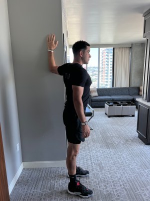Personal trainer demonstrating static wall pec stretch