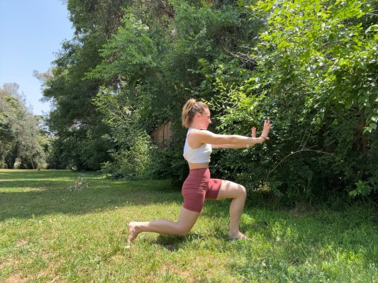 Personal trainer demonstrating power lunge outside. 