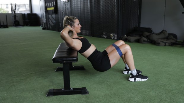Personal trainer demonstrating banded elevated glute bridge