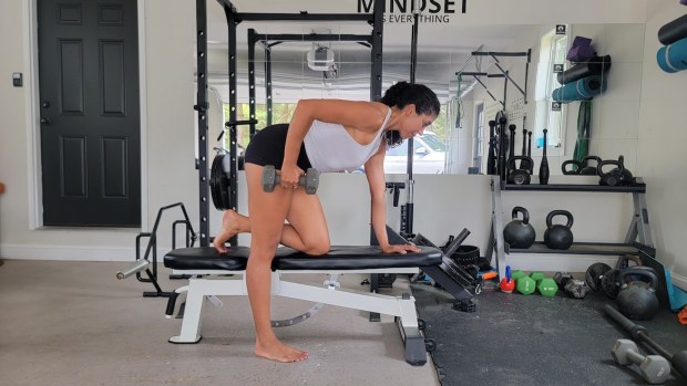 Personal trainer demonstrating bent-over dumbbell row on bench