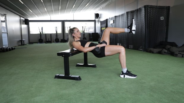 Personal trainer demonstrating single-leg dumbbell hip thrust
