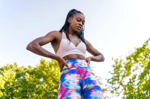 View From Below Of A Young Black Woman With Braids And Colorful Pants, not hungry after a workout where she gave it her all