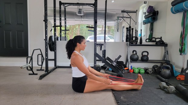 Personal trainer demonstrating seated row with band