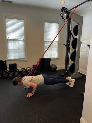 Physical therapist demonstrating band-assisted push-up as push-up alternative