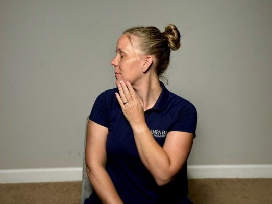 Physical therapist demonstrating chin-to-shoulder stretch as best trapezius exercises