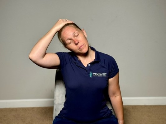 Physical therapist demonstrating ear-to-shoulder stretch as best trapezius exercises