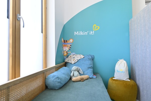 The lactation area inside the Olympic Village Nursery showing a bench, some pillows, and a window.