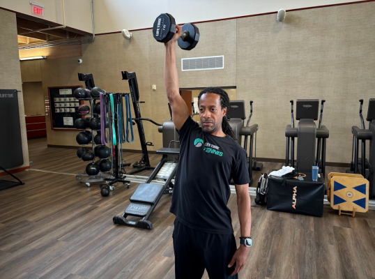 Tennis coach demonstrating single-arm overhead triceps extensio