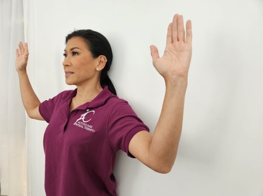 Physical therapist demonstrating wall angel in scapular plane