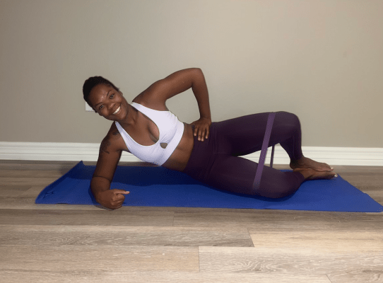 Personal trainer demonstrating banded clamshell exercise