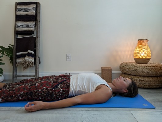 Yoga teacher demonstrating incorrect way to do corpse pose