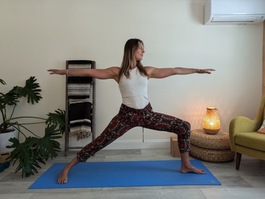 Yoga teacher demonstrating correct way to do warrior II