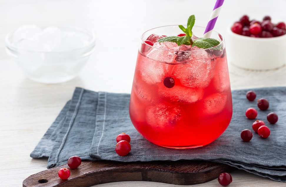 stemless wine glass filled with sparkling cranberry juice and ice cubes sitting on blue napkin