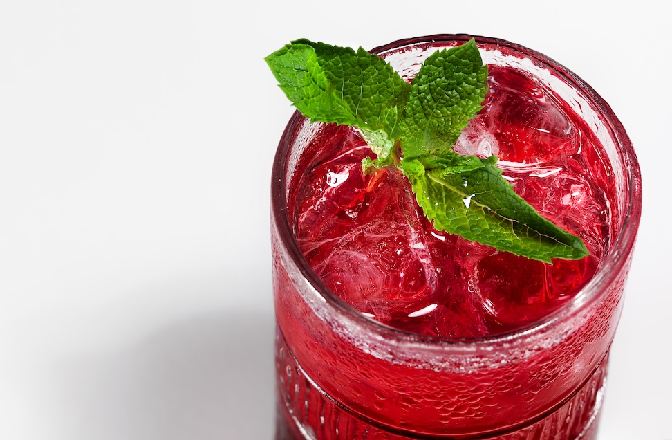 overhead view of sparkling red juice or tea in a glass with a sprig of mint