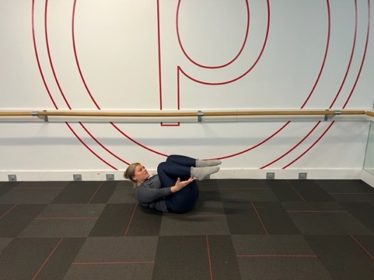 Personal trainer demonstrating a dynamic stretch ab workout in bed