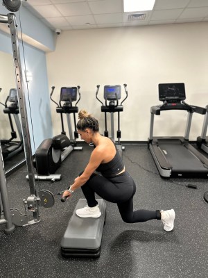 Personal trainer demonstrating cable deficit reverse lunge