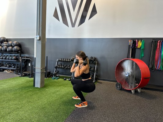 Personal trainer demonstrating dumbbell squat