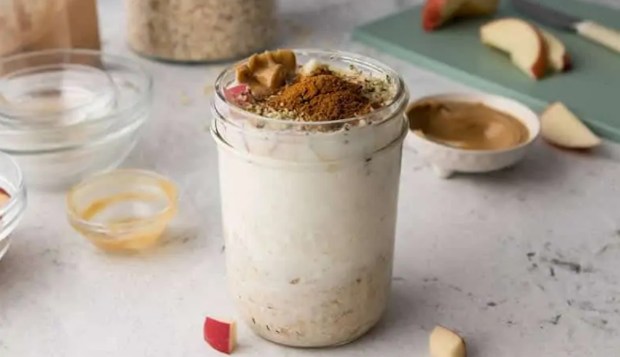 small mason jar filled with apple pie overnight oats with a dash of cinnamon on top