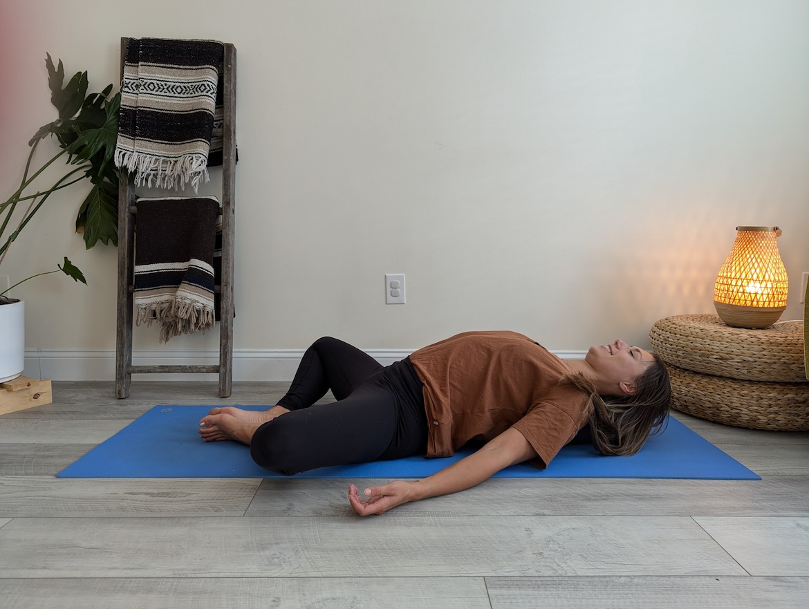 Yoga teacher demonstrating supported cobblers pose with yoga bolster