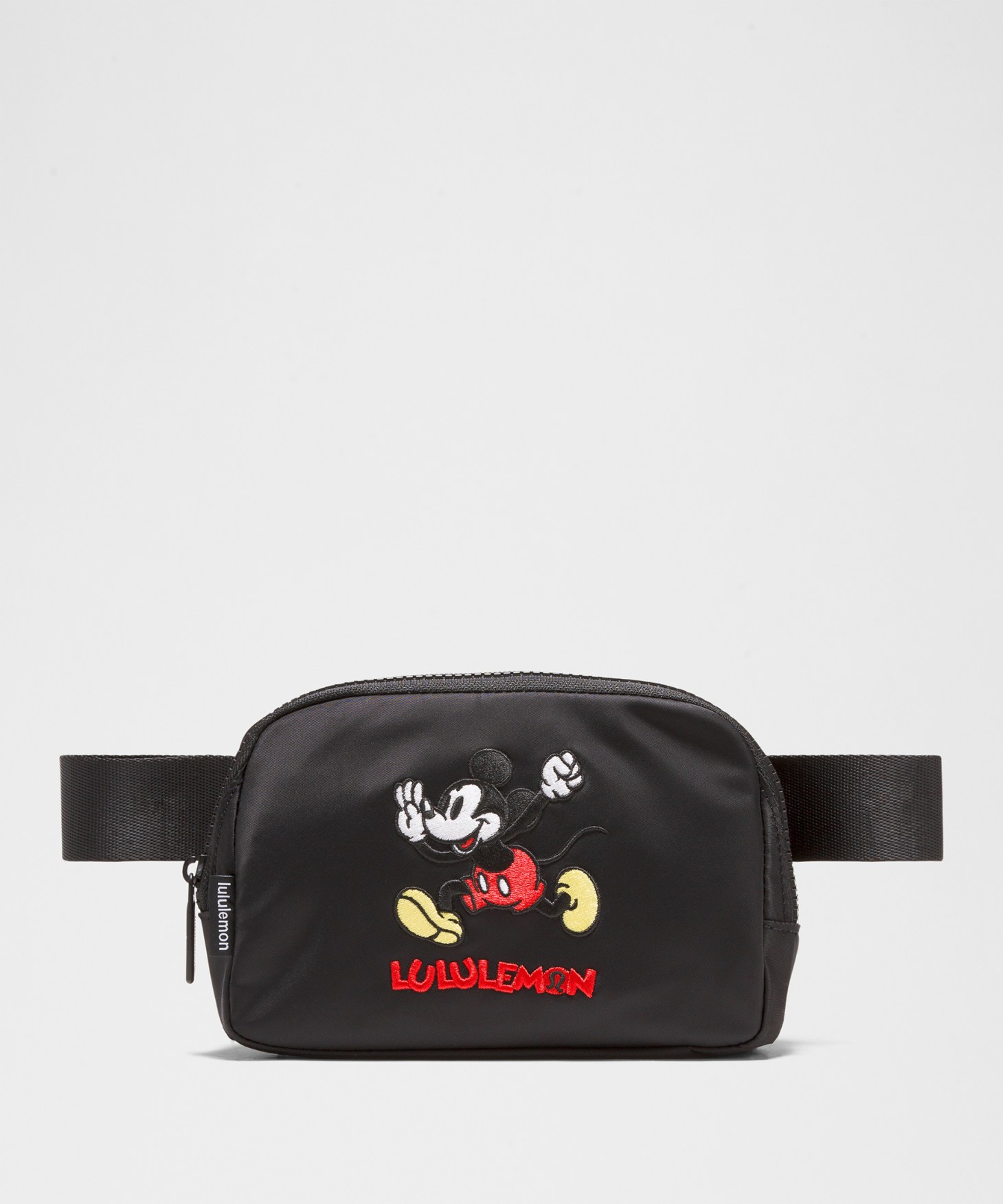 A black fanny pack with a patch of Mickey Mouse running on it.