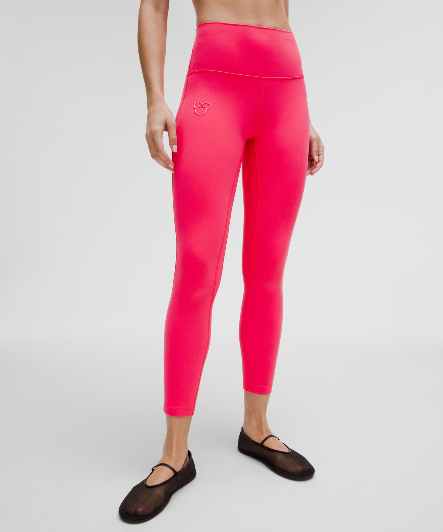 The legs of a woman wearing hot pink cropped leggings.