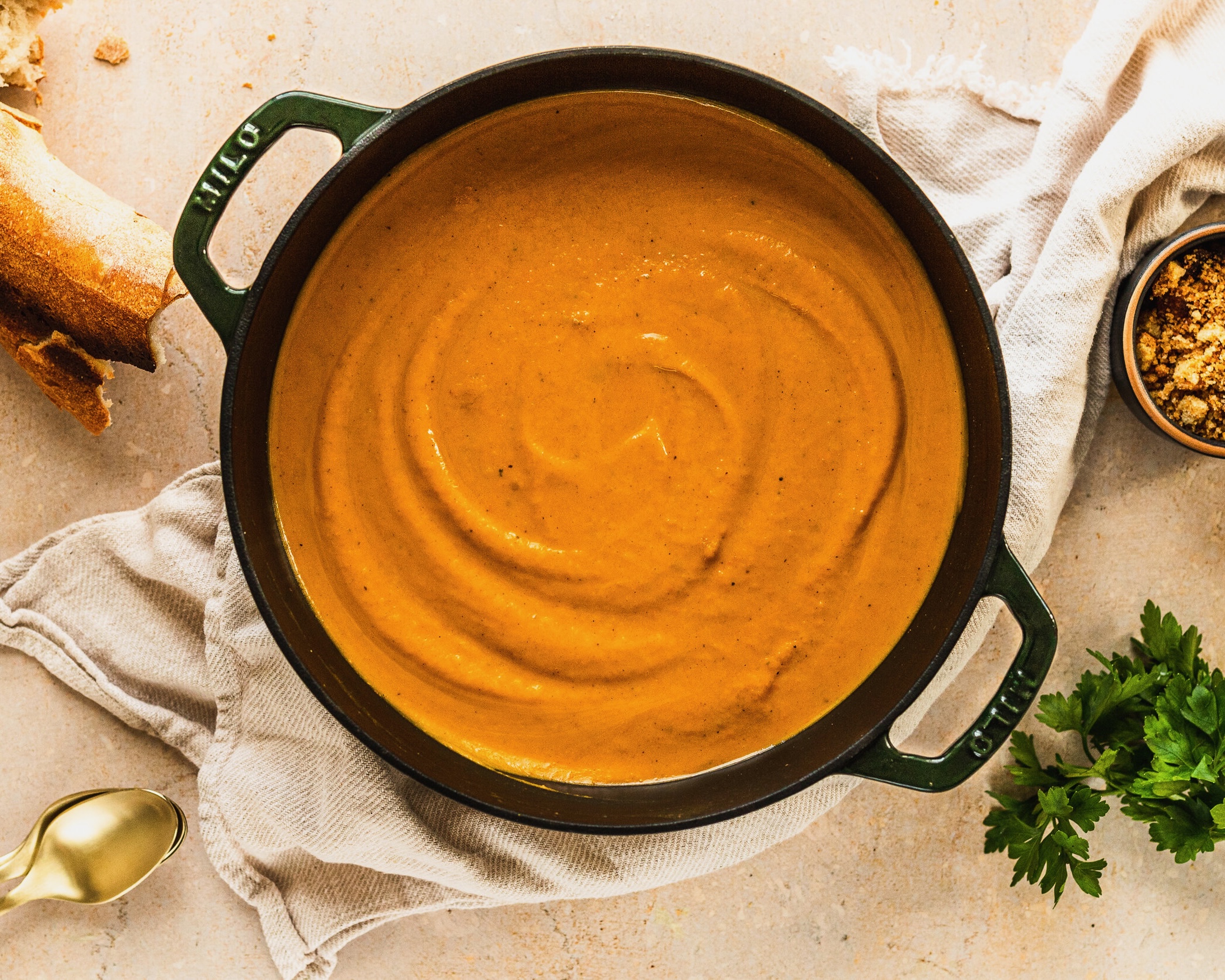 Orange soup in a cast iron Dutch oven resting on a taupe-colored towel 